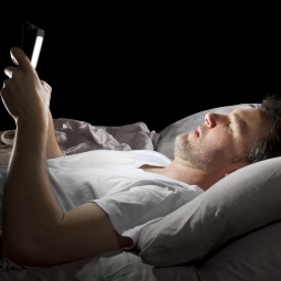 man in bed holding an electronic tablet